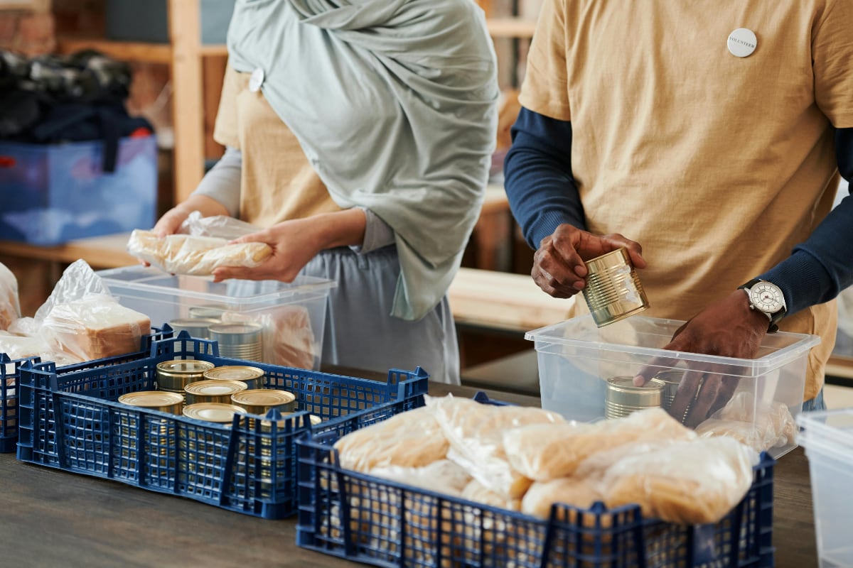 A woman and a man packing crates with food items