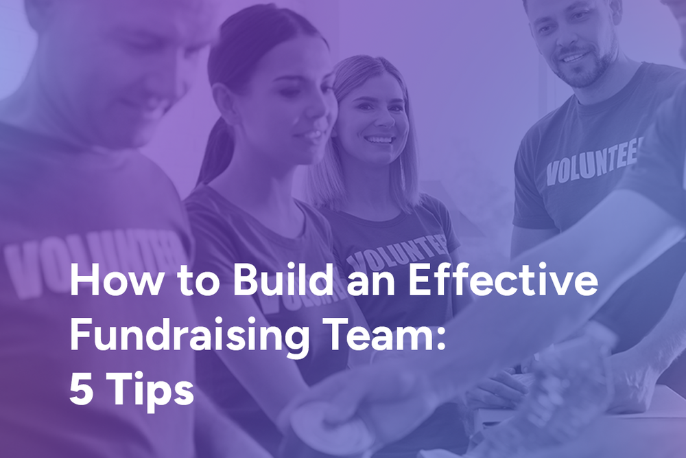 A group of smiling volunteers in matching T-shirts working together at a table